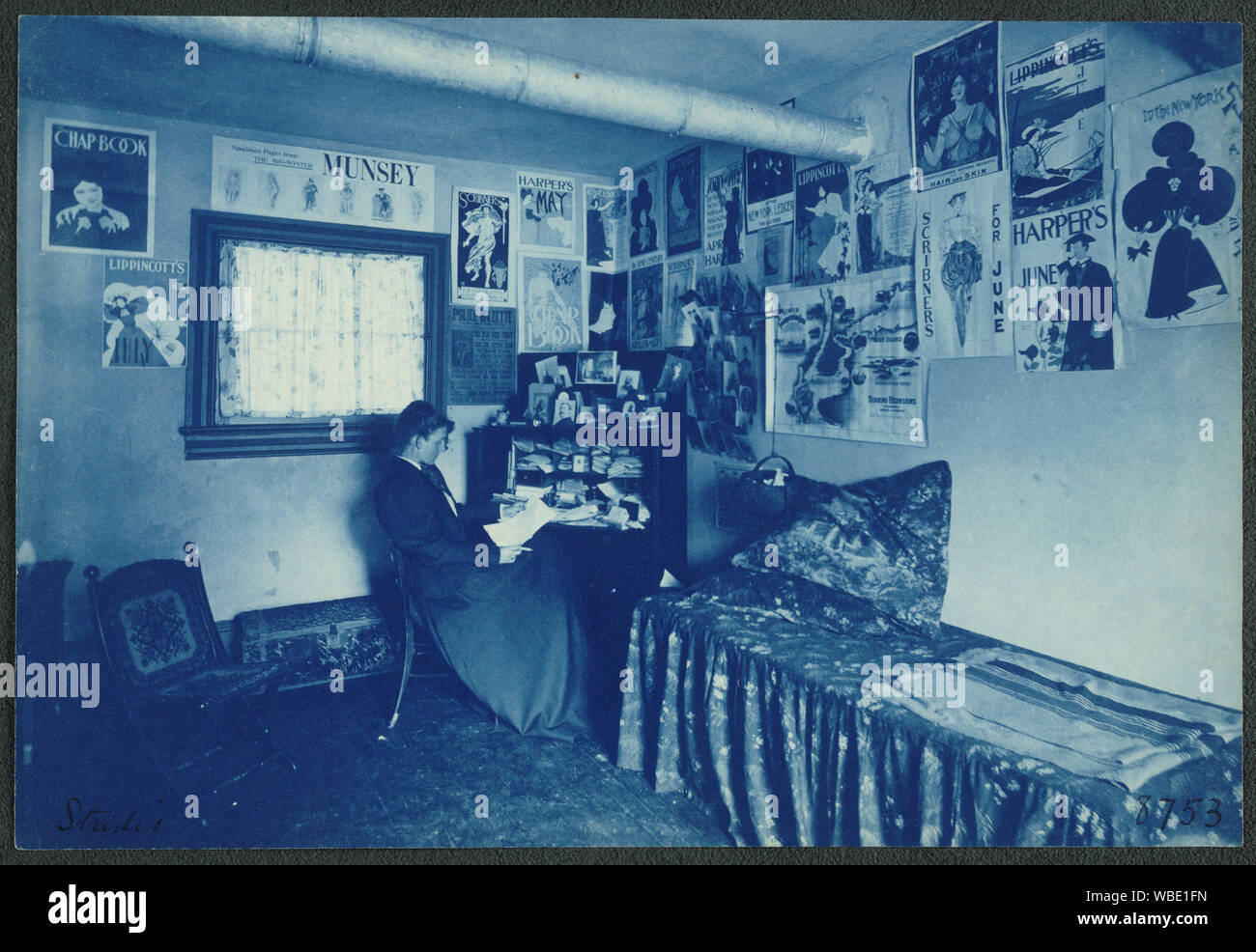 Frances Benjamin Johnston seated at a desk in her studio/office, with adverstising posters on the walls, including the Chap Book, Harper's, and Lippincott's magazines Abstract/medium: 1 photographic print : cyanotype. Stock Photo