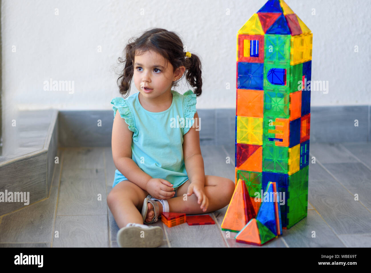 Little girl playing with lots of colorful plastic blocks constructor ...