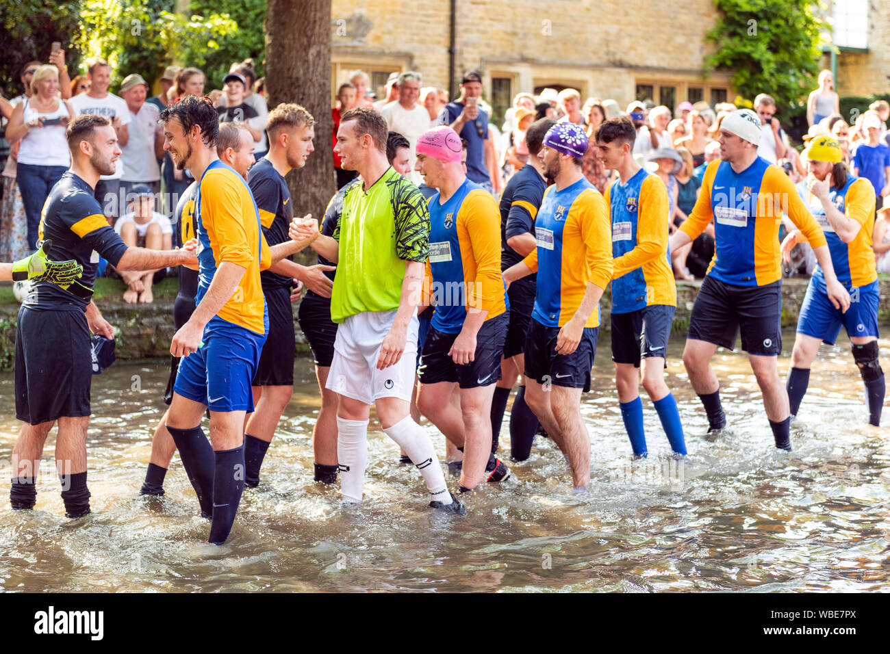 Charity football match played in the River Windrush at Bourton-on-the-Water, Cotswolds, UK. Football game in river on August Bank Holiday Monday. Stock Photo