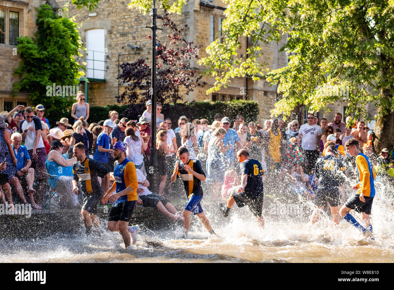 Charity football match played in the River Windrush at Bourton-on-the-Water, Cotswolds, UK. Football game in river on August Bank Holiday Monday. Stock Photo