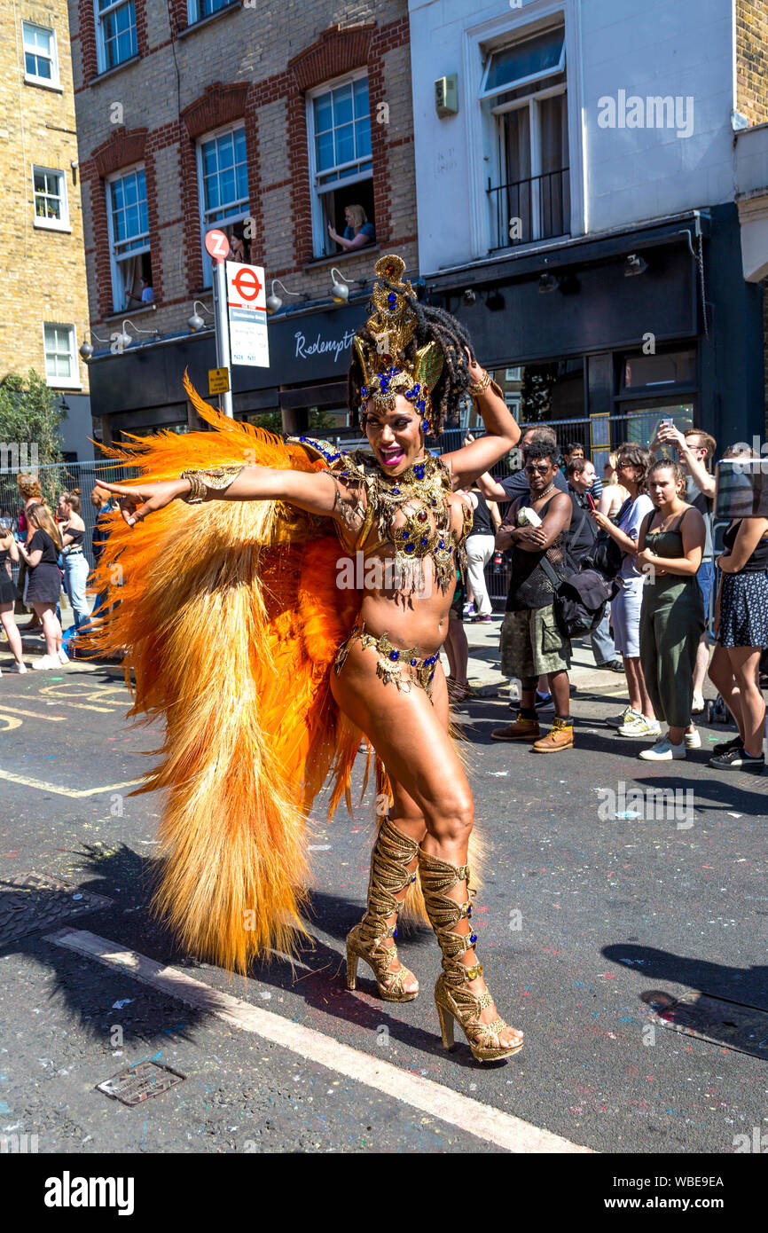 26 August 2019 - Samba dancer with orange feather wings walking in the parade, Notting Hill Carnival on a hot Bank Holiday Monday, London, UK Stock Photo