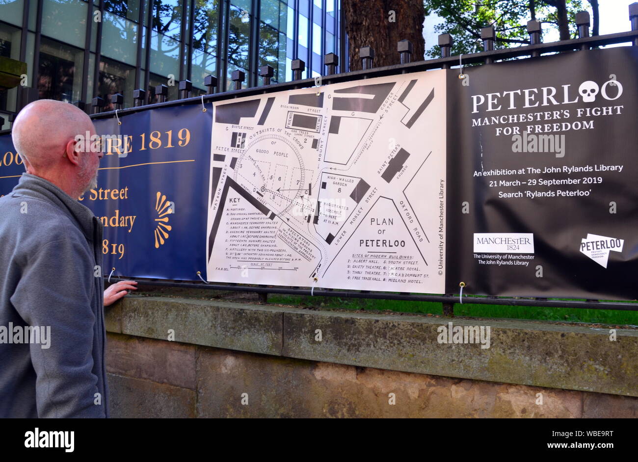 A senior man looks at a map of the Peterloo massacre on the fence of the Friend's Meeting House on Mount Street, central Manchester, At the Peterloo massacre of 1819 the cavalry charged a crowd of some 60,000 people gathered on St Peter's Fields in Manchester to demand the reform of parliamentary representation. Eighteen people were killed and hundreds injured. Stock Photo