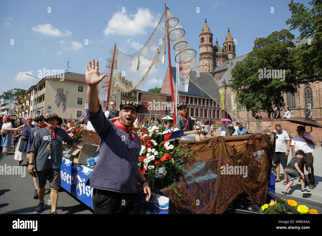 Worms, Germany. 25th August 2019. Members of the old fishermen's guild of Worms march in the parade with a large sailing boat. The first highlight of the 2019 Backfischfest was the big parade through the city of Worms with over 70 groups and floats. Community groups, music groups and businesses from Worms and further afield took part. Stock Photo