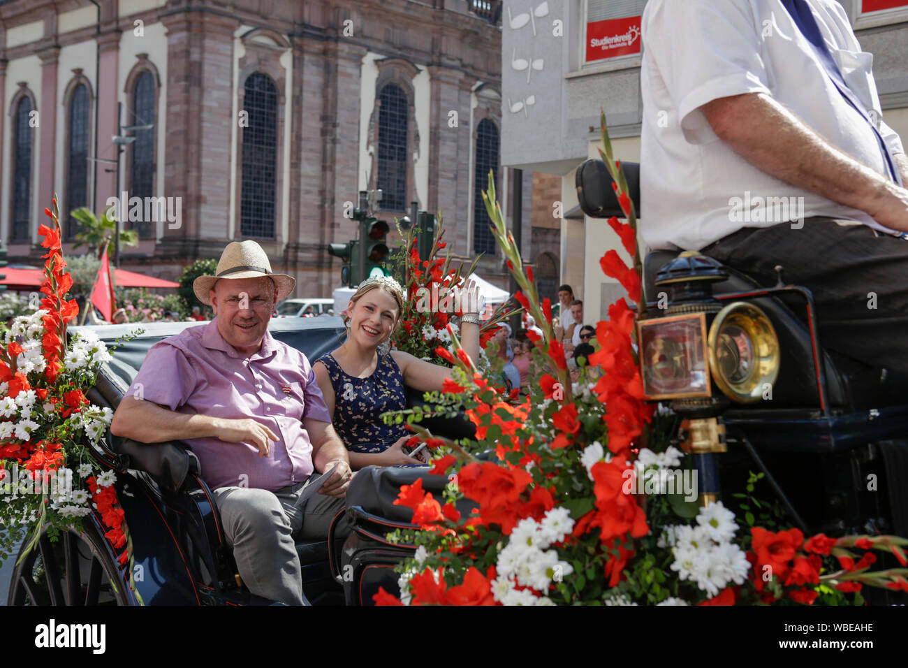 Worms, Germany. 25th August 2019. The Lord Mayor of Worms, Adolf Kessel, and the Rhine-Hessian wine queen Anna Göhring ride in an open horse-drawn carriage in the parade, waving to the crowd. The first highlight of the 2019 Backfischfest was the big parade through the city of Worms with over 70 groups and floats. Community groups, music groups and businesses from Worms and further afield took part. Stock Photo