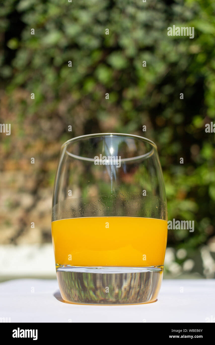 A glass of fresh orange juice outdoors on a sunny day with out of ...