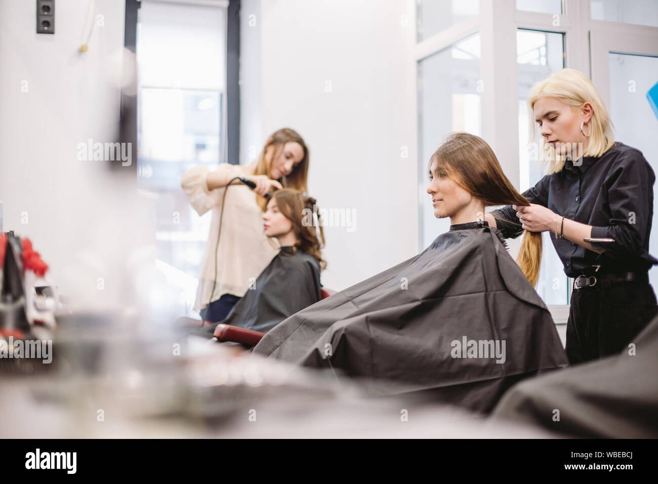 beautiful woman combing wet hair. stylist brushing woman hair in salon. Hairdresser Serving Customer. Professional Young Hairdresser Working With Comb Stock Photo