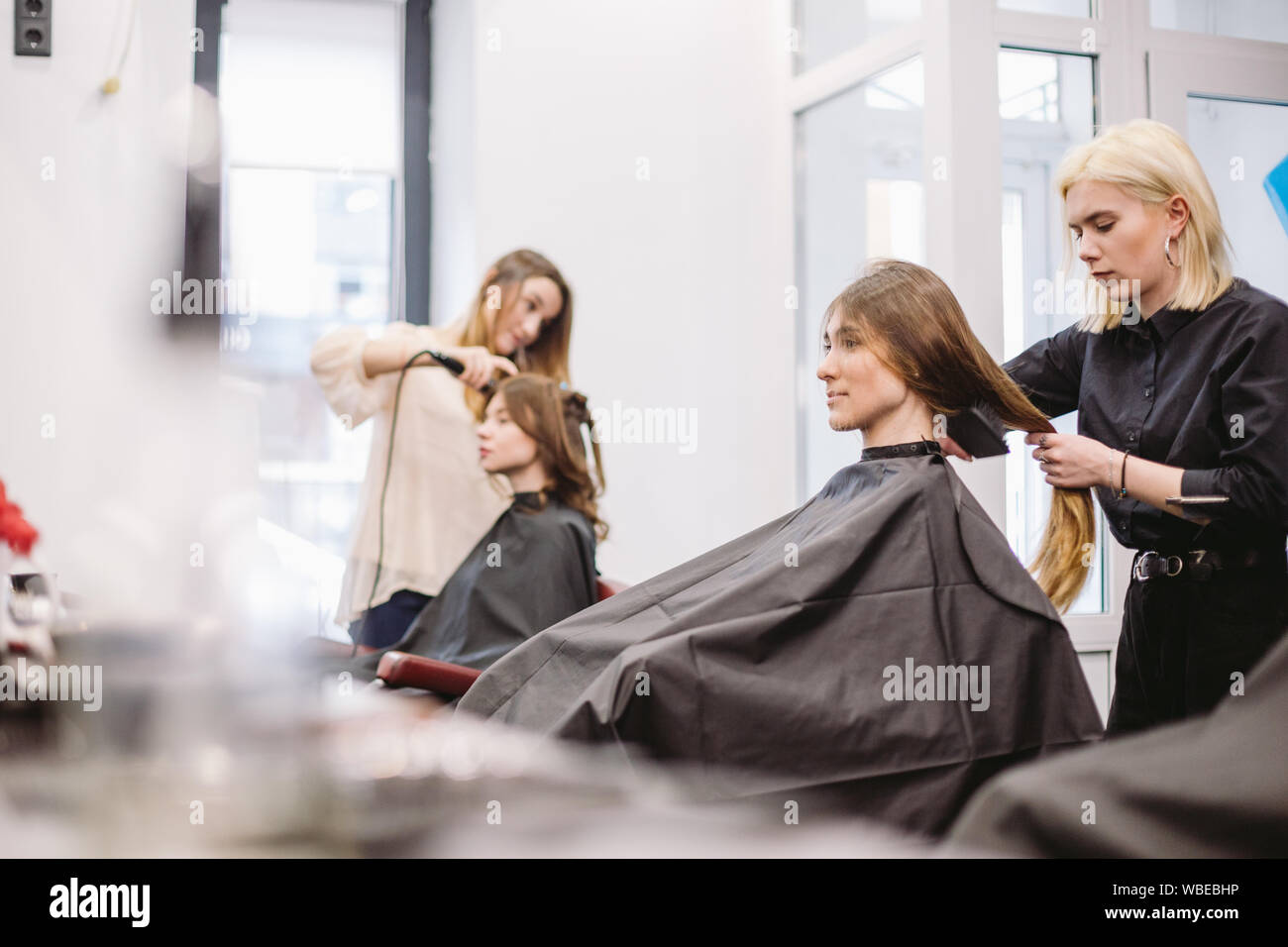 beautiful woman combing wet hair. stylist brushing woman hair in salon. Hairdresser Serving Customer. Professional Young Hairdresser Working With Comb Stock Photo