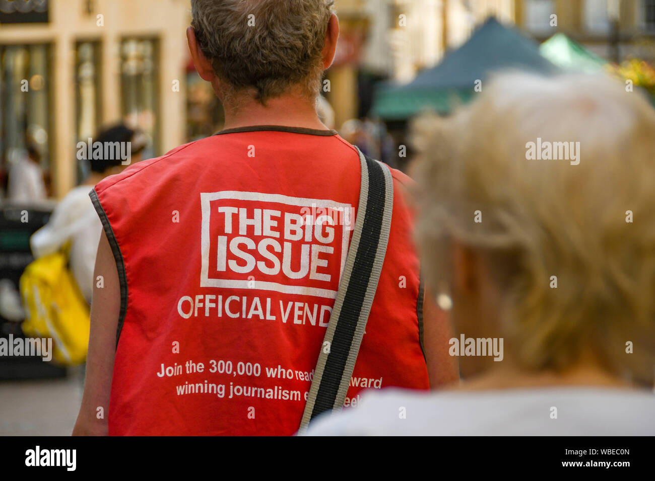 BATH, ENGLAND - JULY 2019: Person selling The Big Issue magazine on a street in Bath city centre. Stock Photo