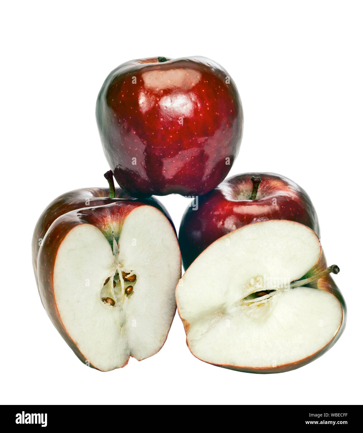 Vertical shot of four shiny red apples on a white background.  One apple is balanced on two others.  The fourth apple has been cup open and is in fron Stock Photo
