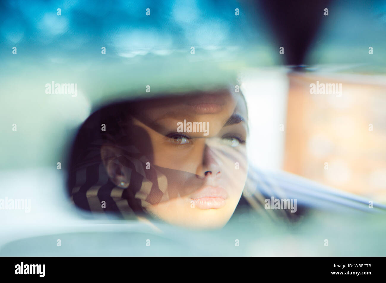 Portrait In Rear View Mirror Beautiful woman driver reflecting in the rear view mirror. Driving her ...
