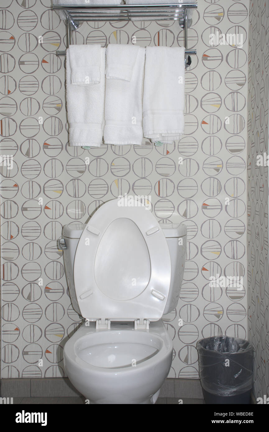 view of white toilet with towel rack above with white towels Stock Photo Alamy