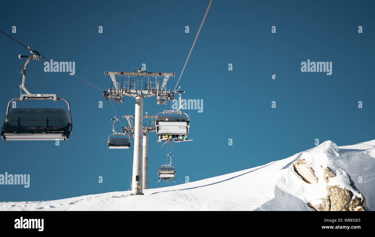 Wide shot of ropeways and gray pillar on a snowy surface under a clear ...