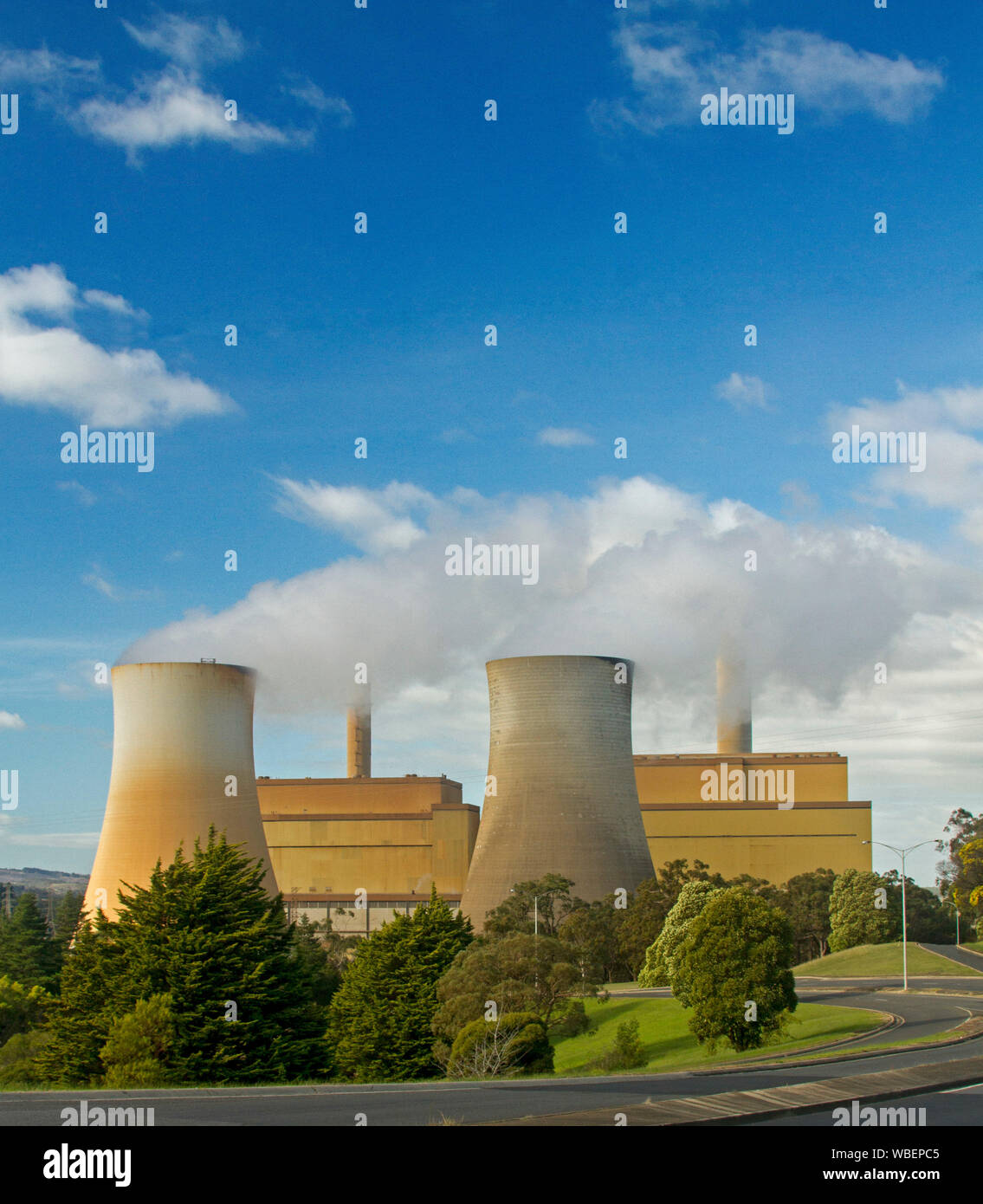 Yallourn North coal fired power station with smoke from tall towers rising into blue sky, Victoria Australia Stock Photo