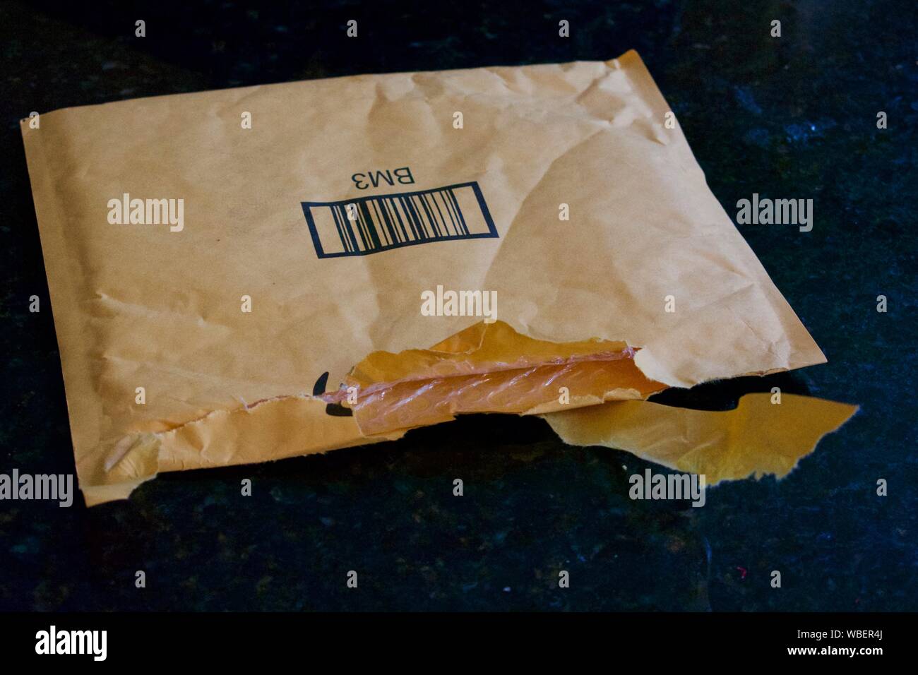 Package ripped open and sitting on top of black counter. Stock Photo