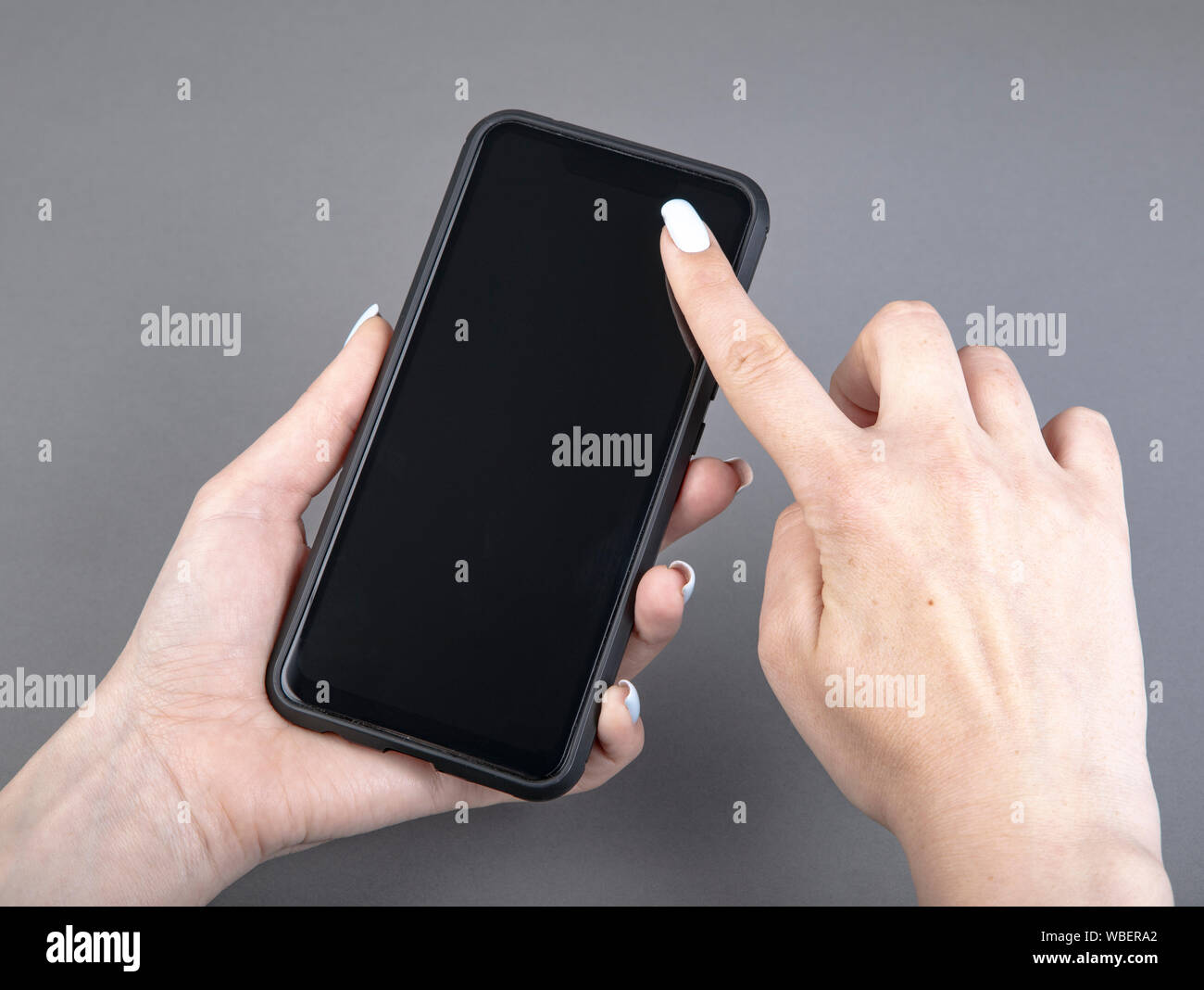 Womans hand holding black screen mobile phone Stock Photo