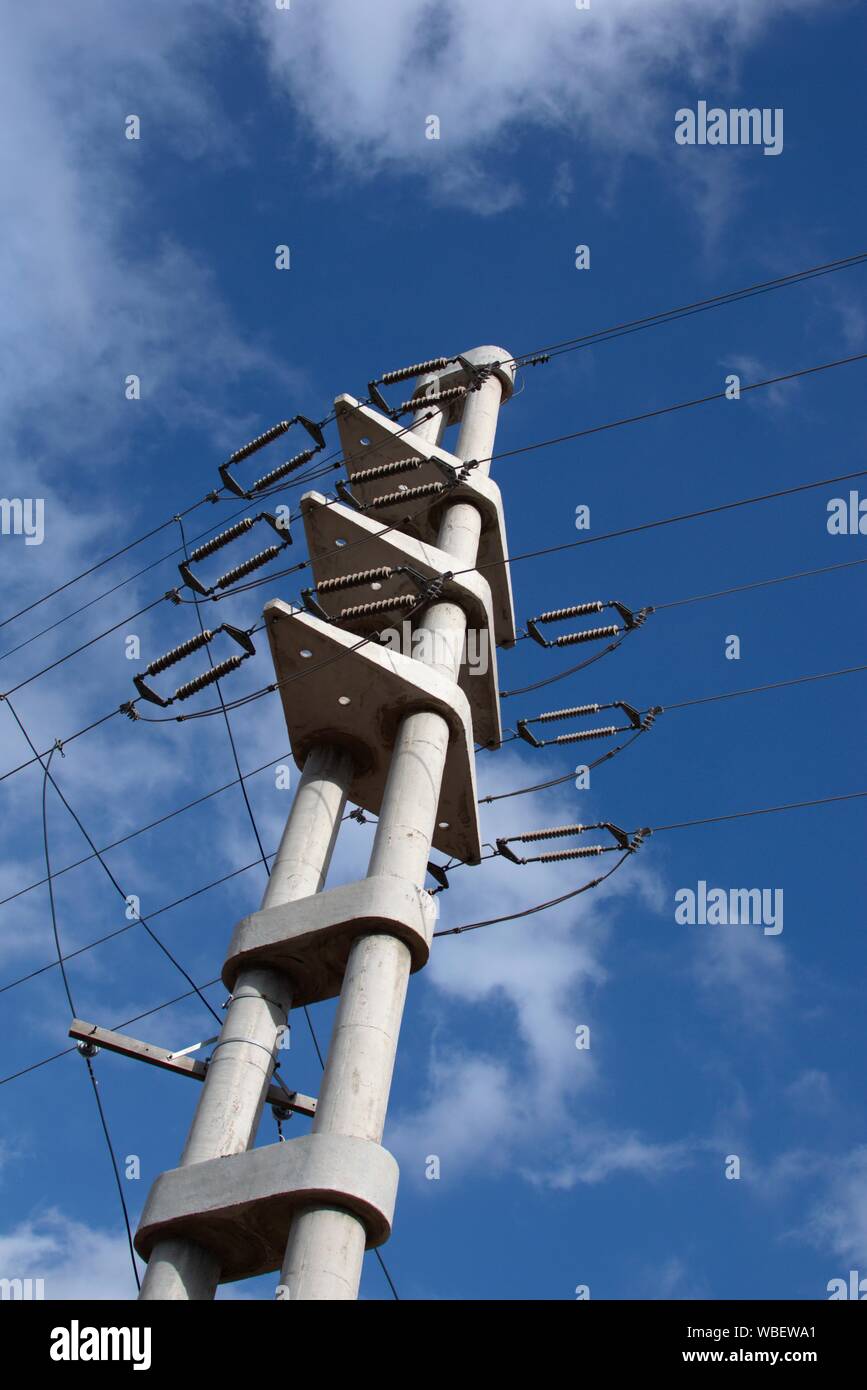 An concrete electrical pylon stands tall against the blue sky. Ceramic