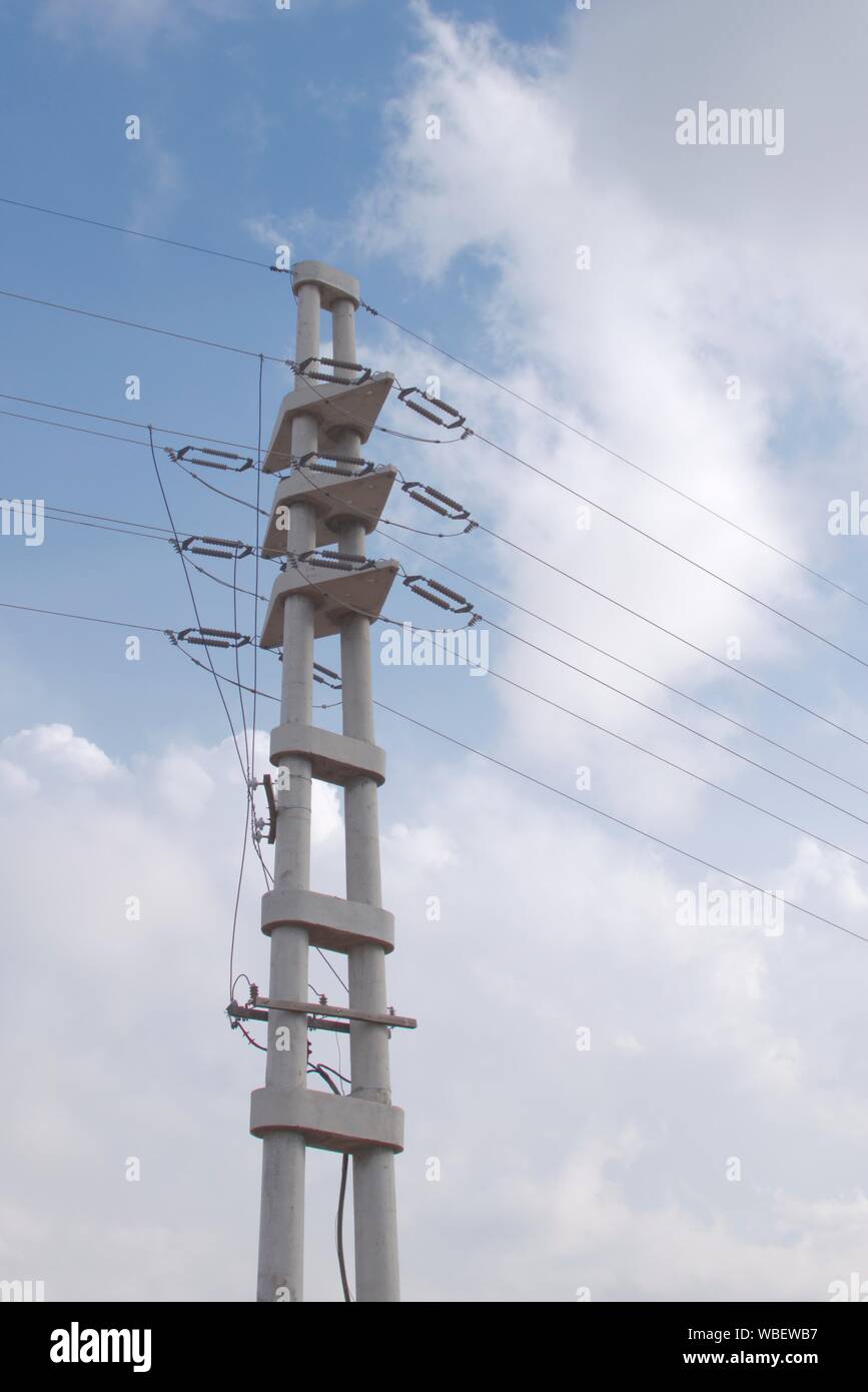 An concrete electrical pylon stands tall against the blue sky. Ceramic