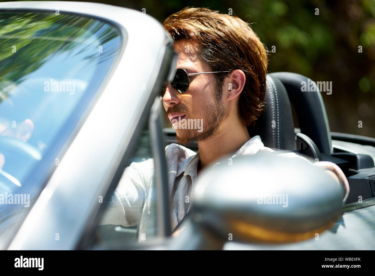 young asian man driving a convertible car, close-up shot Stock Photo