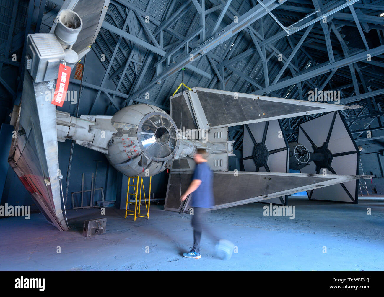 Dassow, Germany. 26th Aug, 2019. Marc Langrock, Star Wars fan and founder of the fan project 'Outpost One', passes the replica of the space interceptor Tie Intercepter in the hangar. The collection of the 'Outpost One' fan project features a total of 29 replica set scenes from various films in the Star Wars series. The over 1,300 square metre show will be officially opened after the first test weeks on 07.09.2019. Credit: dpa picture alliance/Alamy Live News Stock Photo