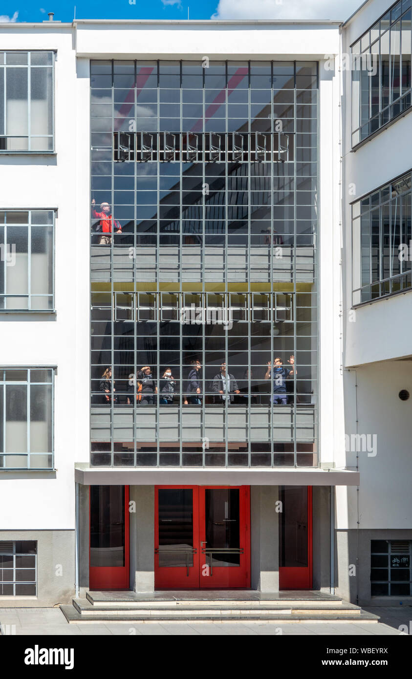People visitors visiting the Dessau Bauhaus Building with guided tour. Teacher tour guide explaining opening trying out the special window system. Stock Photo