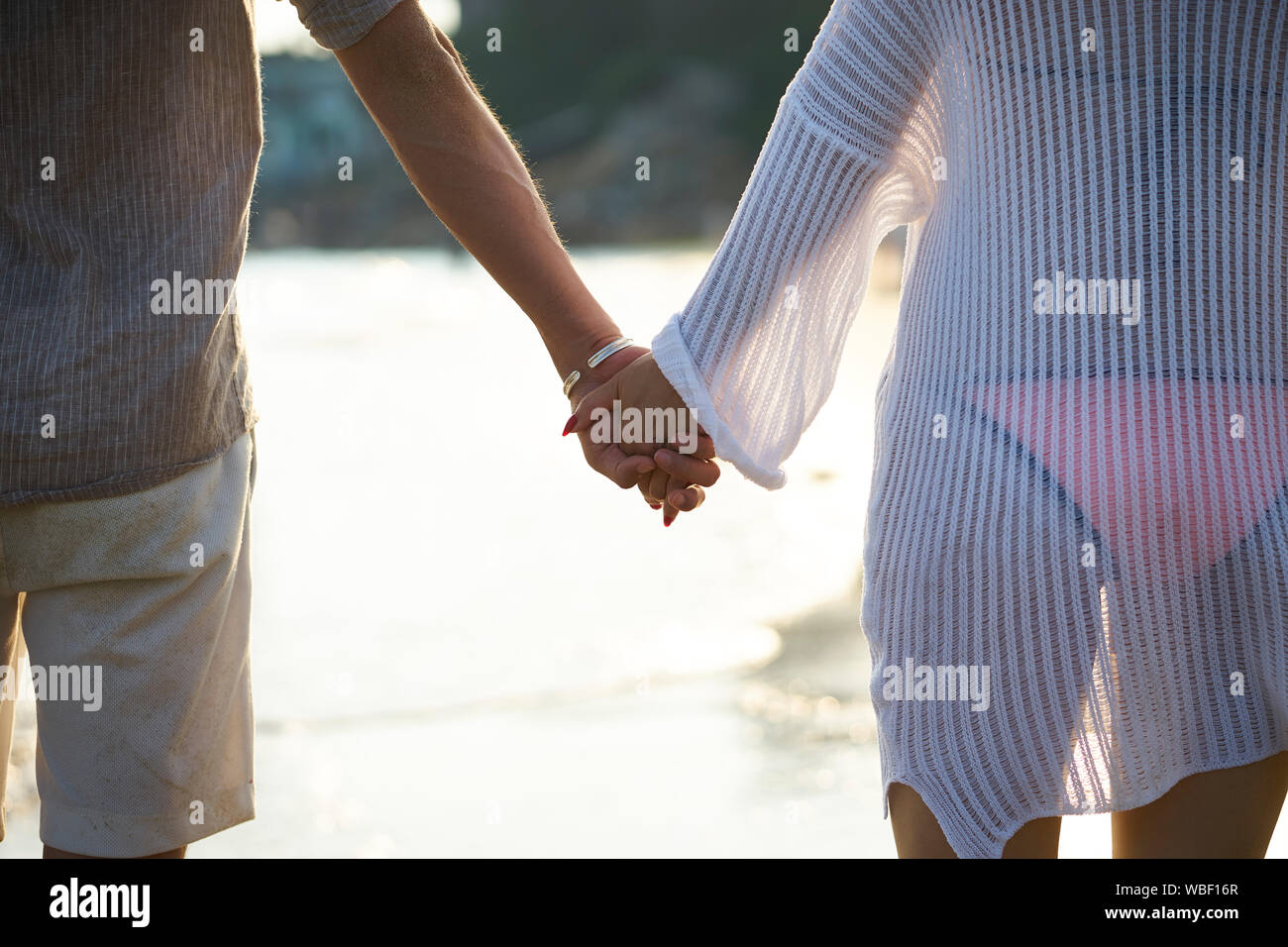 young asian couple holding hands walking on beach Stock Photo