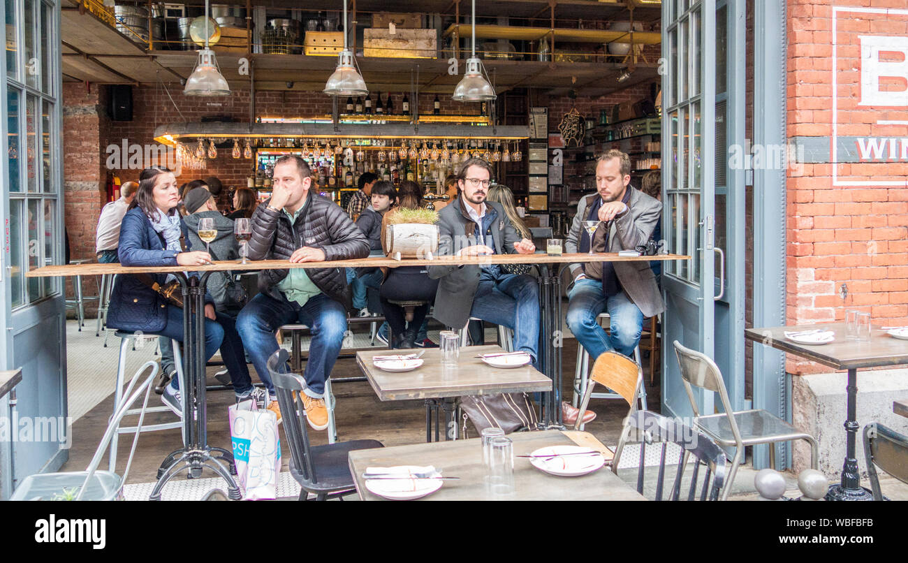 New York, New York - Nov 4, 2014: People sit at a table in Little Italy and watch the world go by Stock Photo