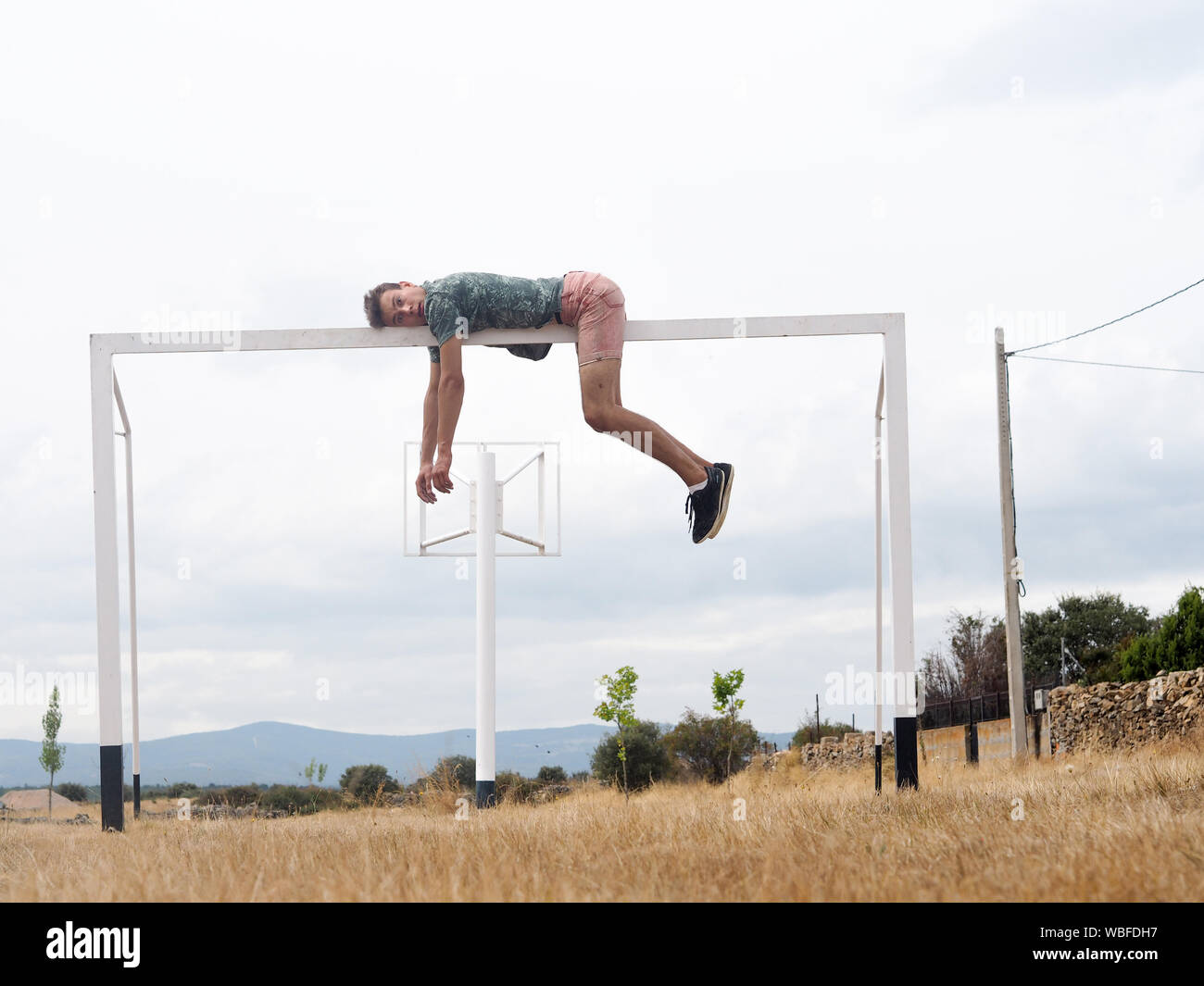 Full Length Of Man Lying On Soccer Goal Post Against Sky Stock Photo