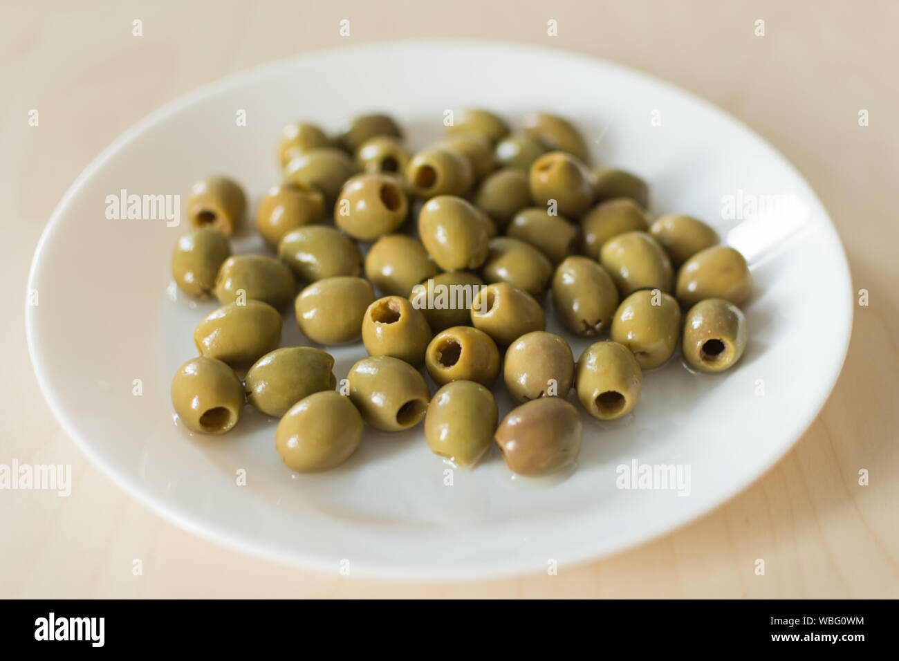 Pickled green olives in a plate on a white background Olives, healthy eating. Italian cuisine. Stock Photo