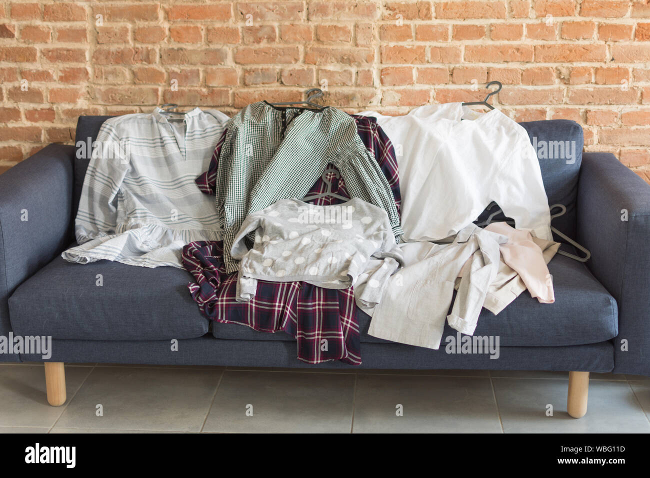 Mess of clothers on the sofa. What to wear concept. Messy colorful clothing  on a sofa Stock Photo - Alamy