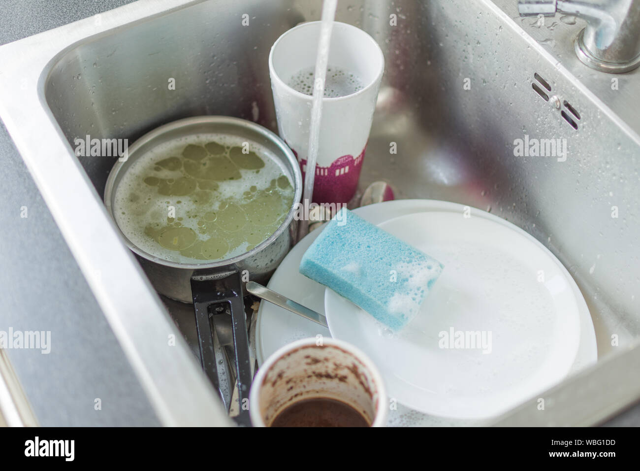 Unwashed dishes and utensils in a kitchen sink. Pile of dirty dishes in