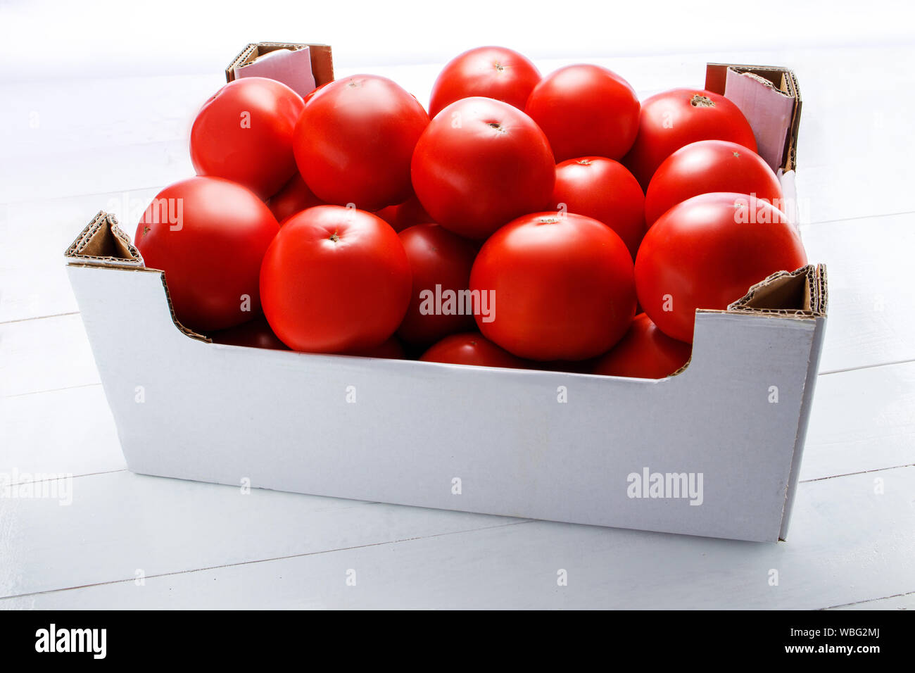 Fresh assorted tomatoes in cardboard boxes on white background Stock