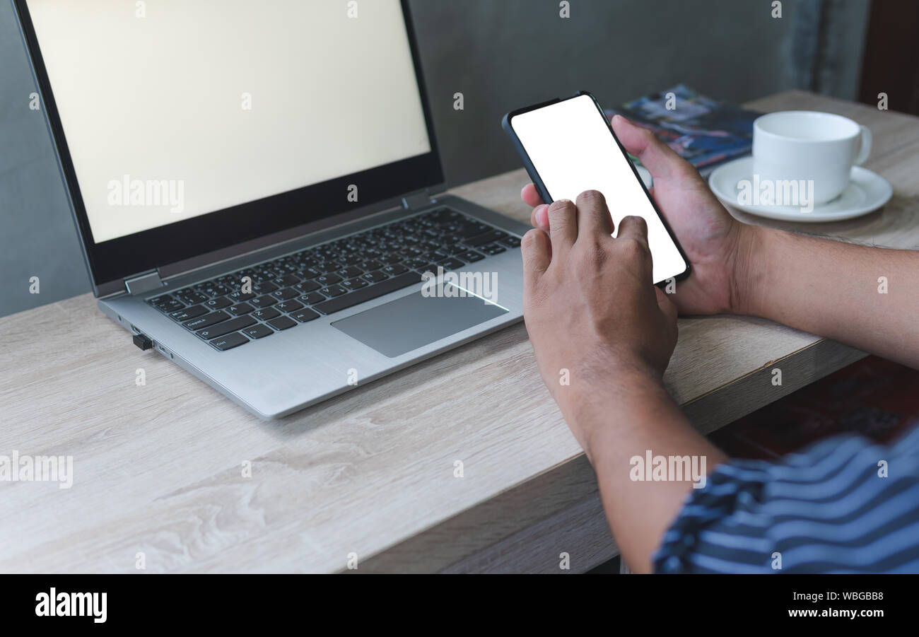 Business man hand holding smart mobile phone, using credit card for online shopping with laptop computer and digital tablet on table. Cyber concept Stock Photo