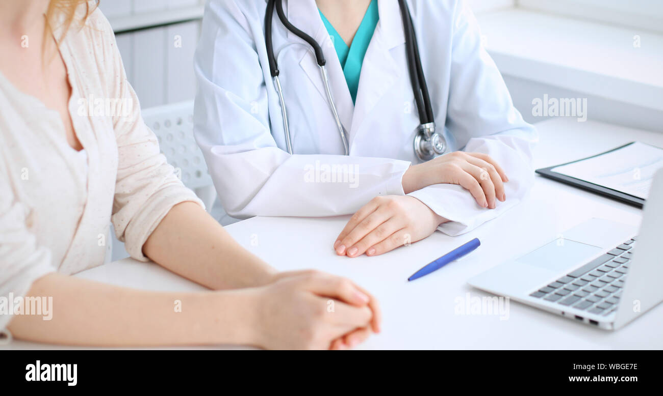 Doctor and patient discussing something while sitting at the desk at ...