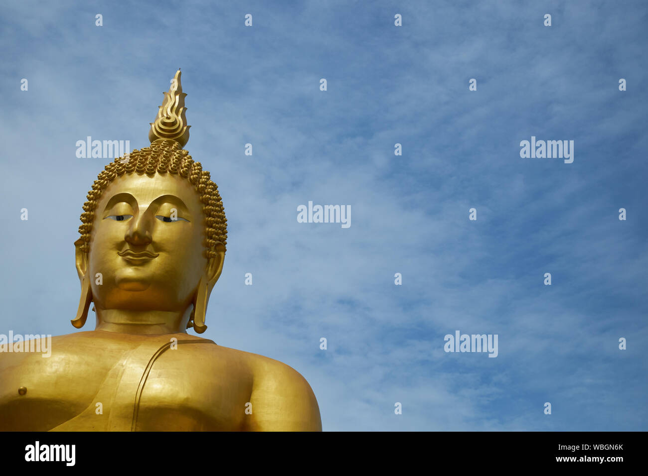 A giant, gold, sitting Buddha at Wat Muang in Ang Thong, Thailand. Empty, negative space for text, information. Stock Photo