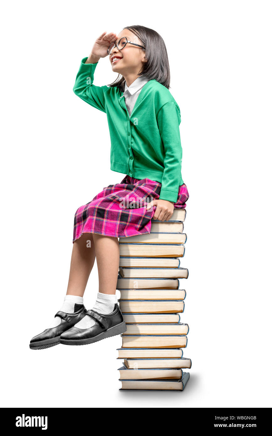 Asian cute girl with glasses sitting on the pile of books and looking forward isolated over white background Stock Photo