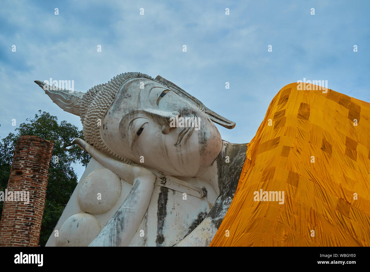 A closeup of the head of the lovely reclining Buddha, complete with orange robe, at Wat Khun Inthapramun in Ang Thong, Thailand. Stock Photo
