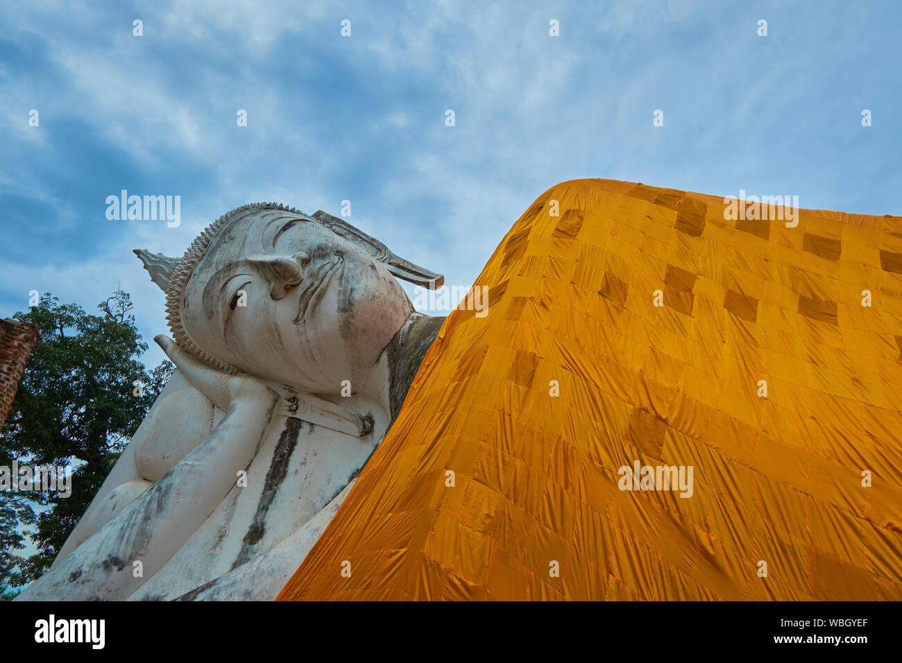 A closeup of the head of the lovely reclining Buddha, complete with orange robe, at Wat Khun Inthapramun in Ang Thong, Thailand. Stock Photo