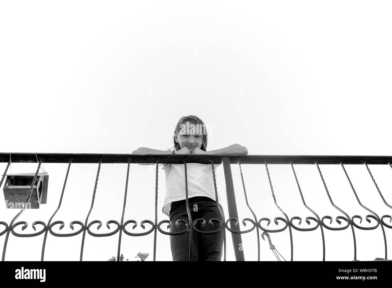 Girl 9 years old stand near the iron fence. Photo taken from below. Black White. Stock Photo