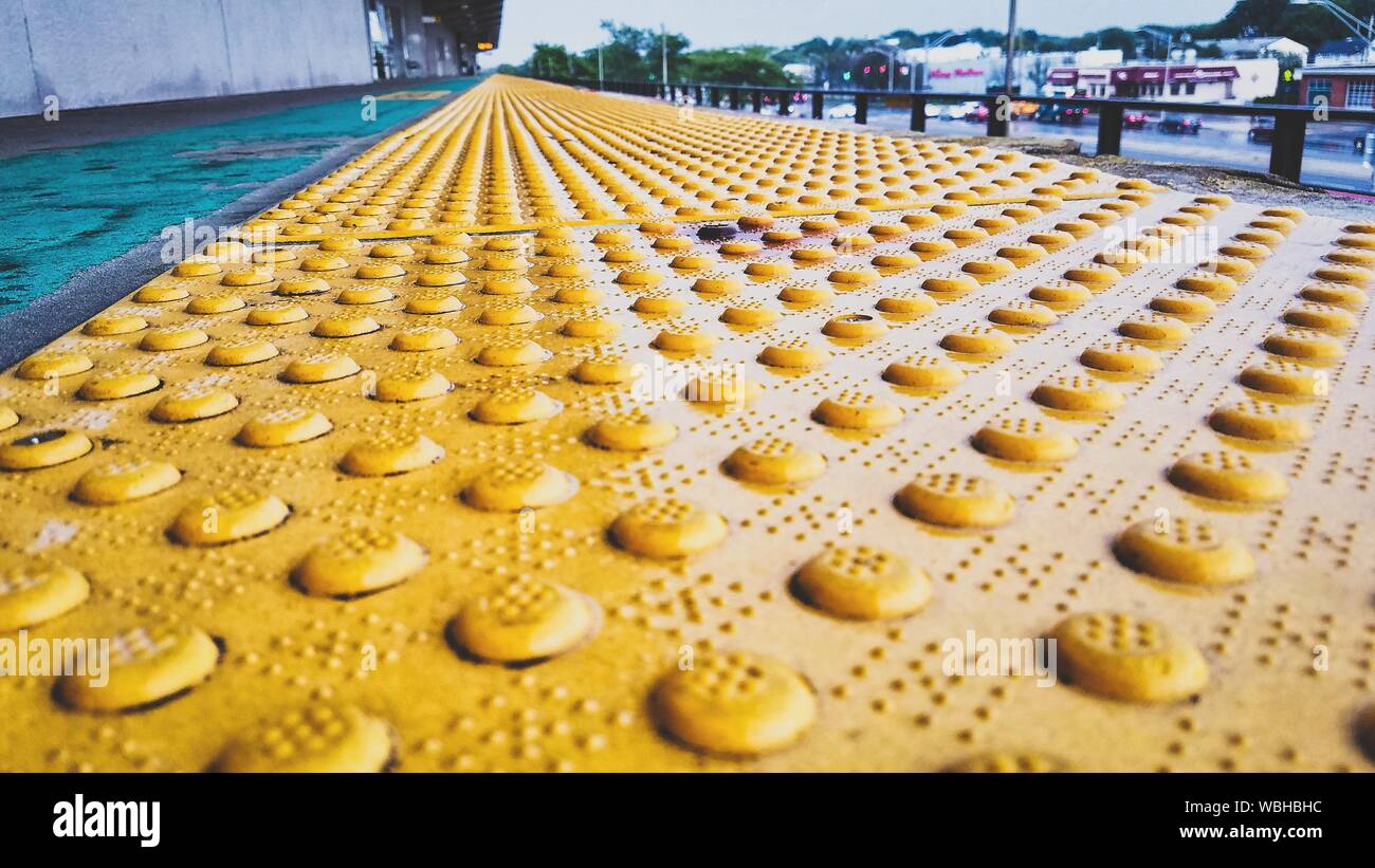 Surface Level View Of Yellow Metallic Tactile Walkway In City Stock Photo