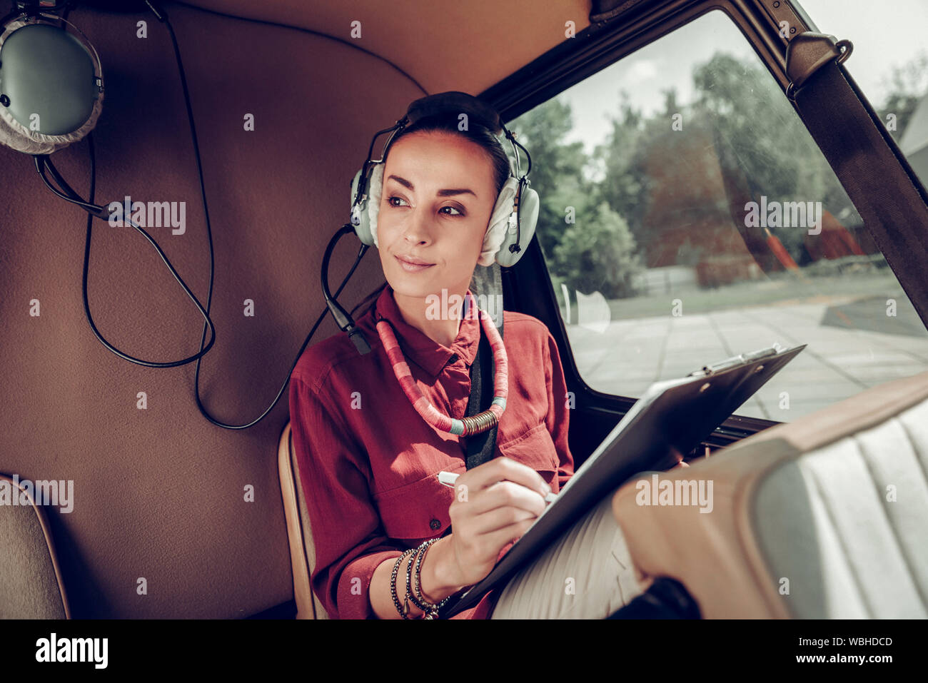 Businesswoman making some notes while flying in helicopter Stock Photo