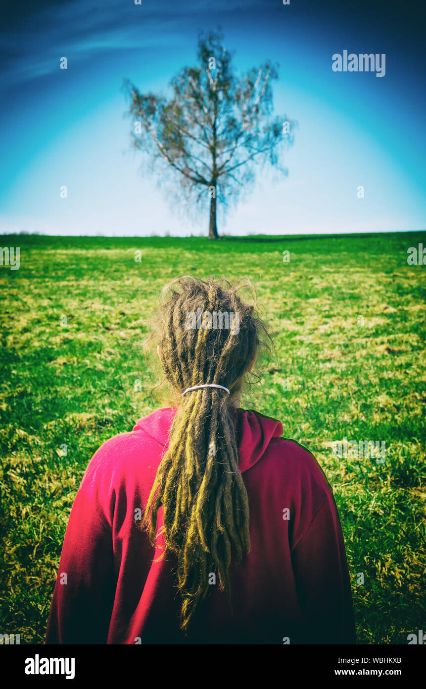 Rear View Of Woman With Dreadlocks Standing On Field Stock Photo
