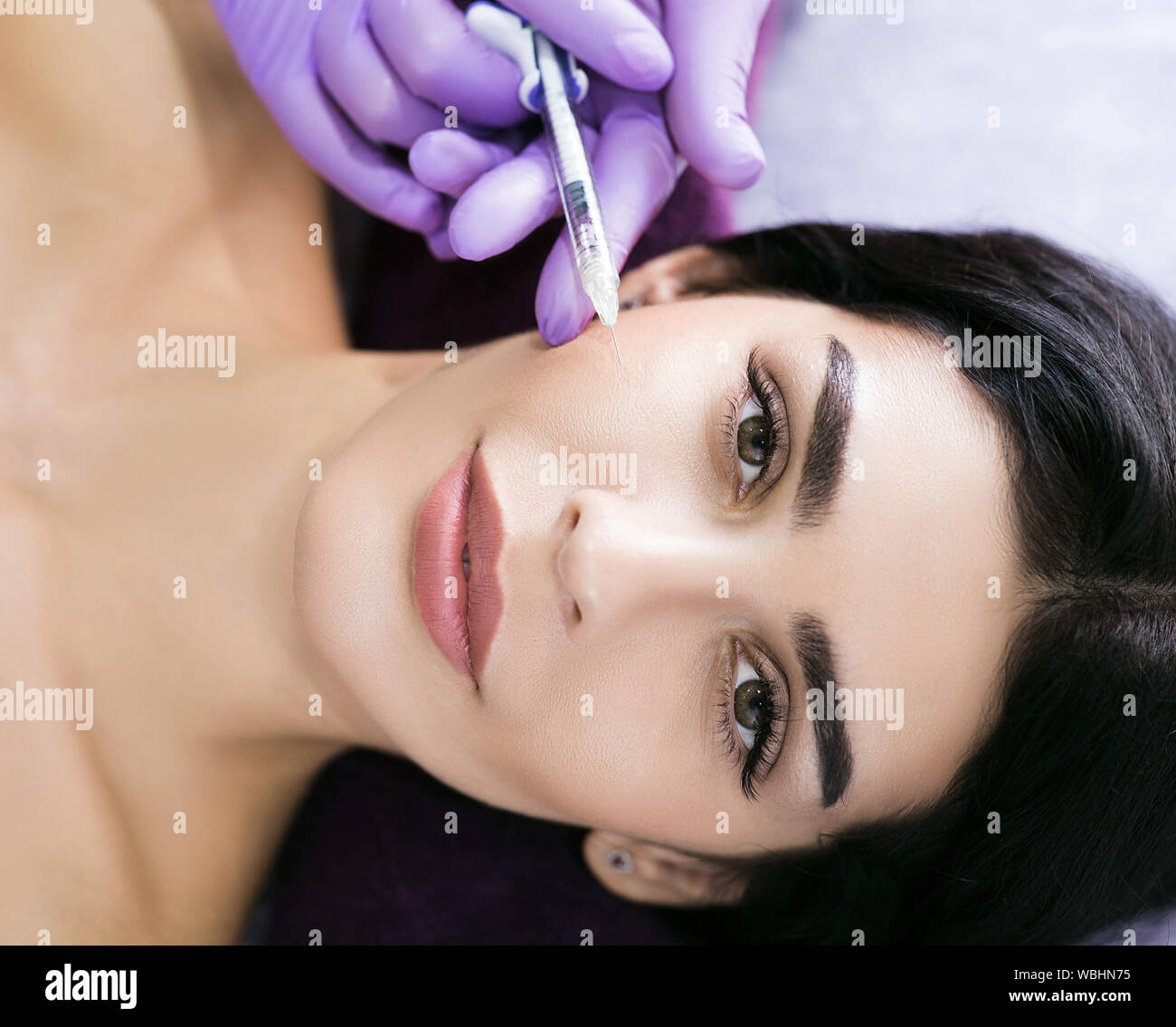 Beauty injections close up. A beautiful mid-aged brunette gets injections of beauty, anti wrinkles therapy, skin rejuvenation Stock Photo