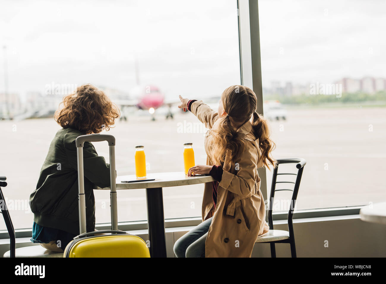 preteen kid pointing with finger at plane and boy looking on it Stock Photo