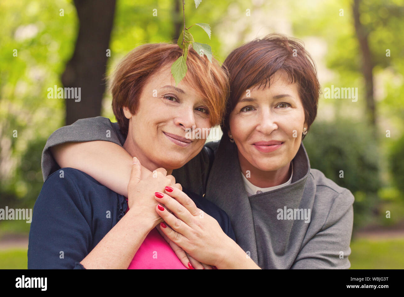 Two happy women walking in summer park, portrait Stock Photo - Alamy