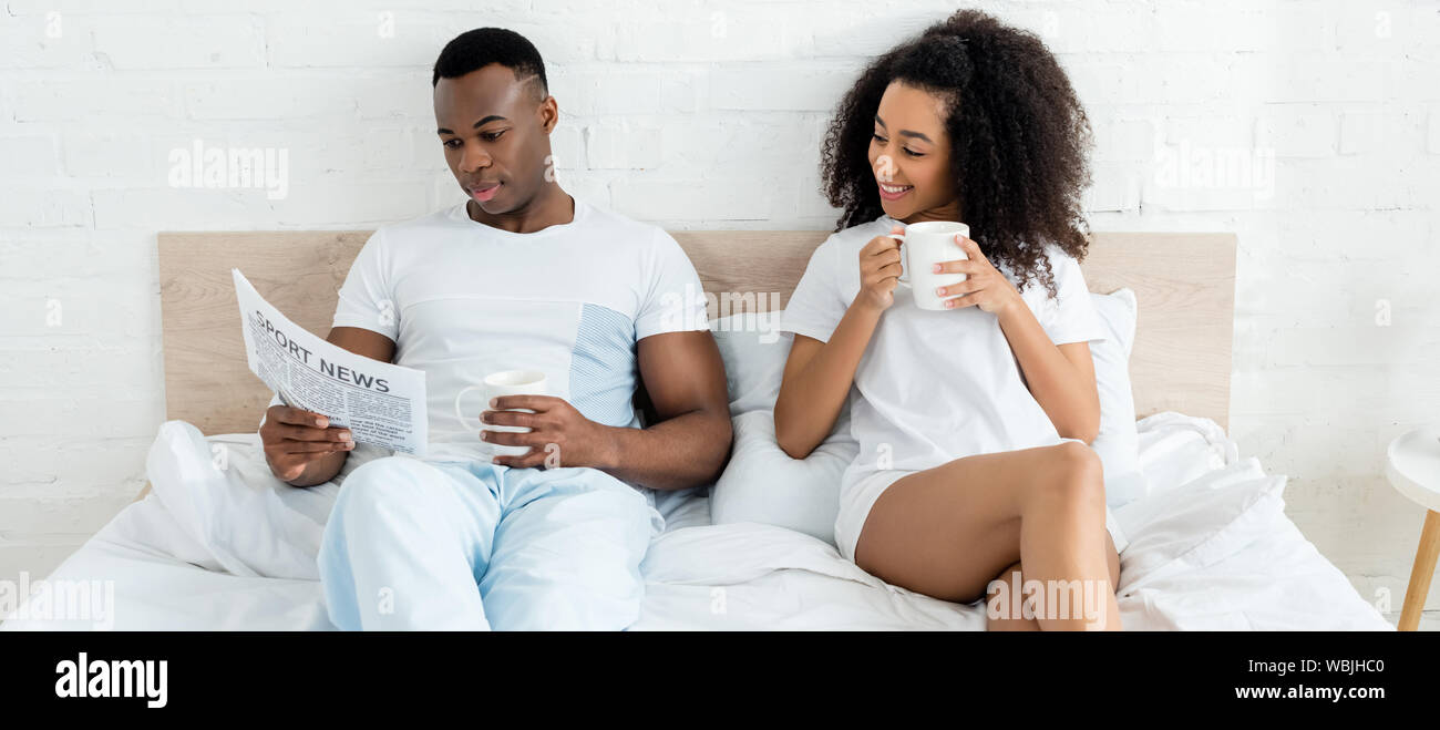 african american couple spending morning in bed with newspaper and cup ...