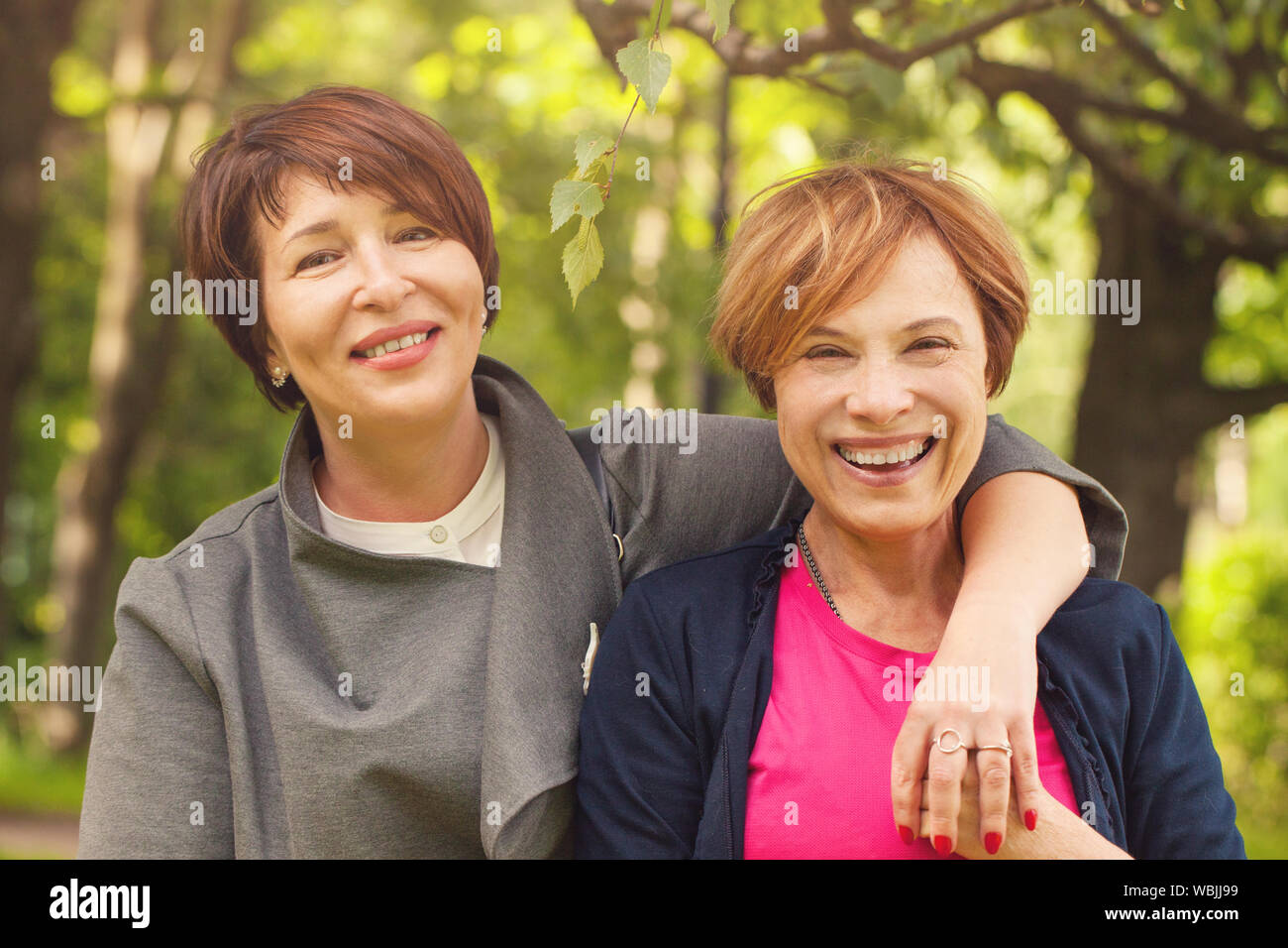 Two happy women walking in summer park, portrait Stock Photo - Alamy