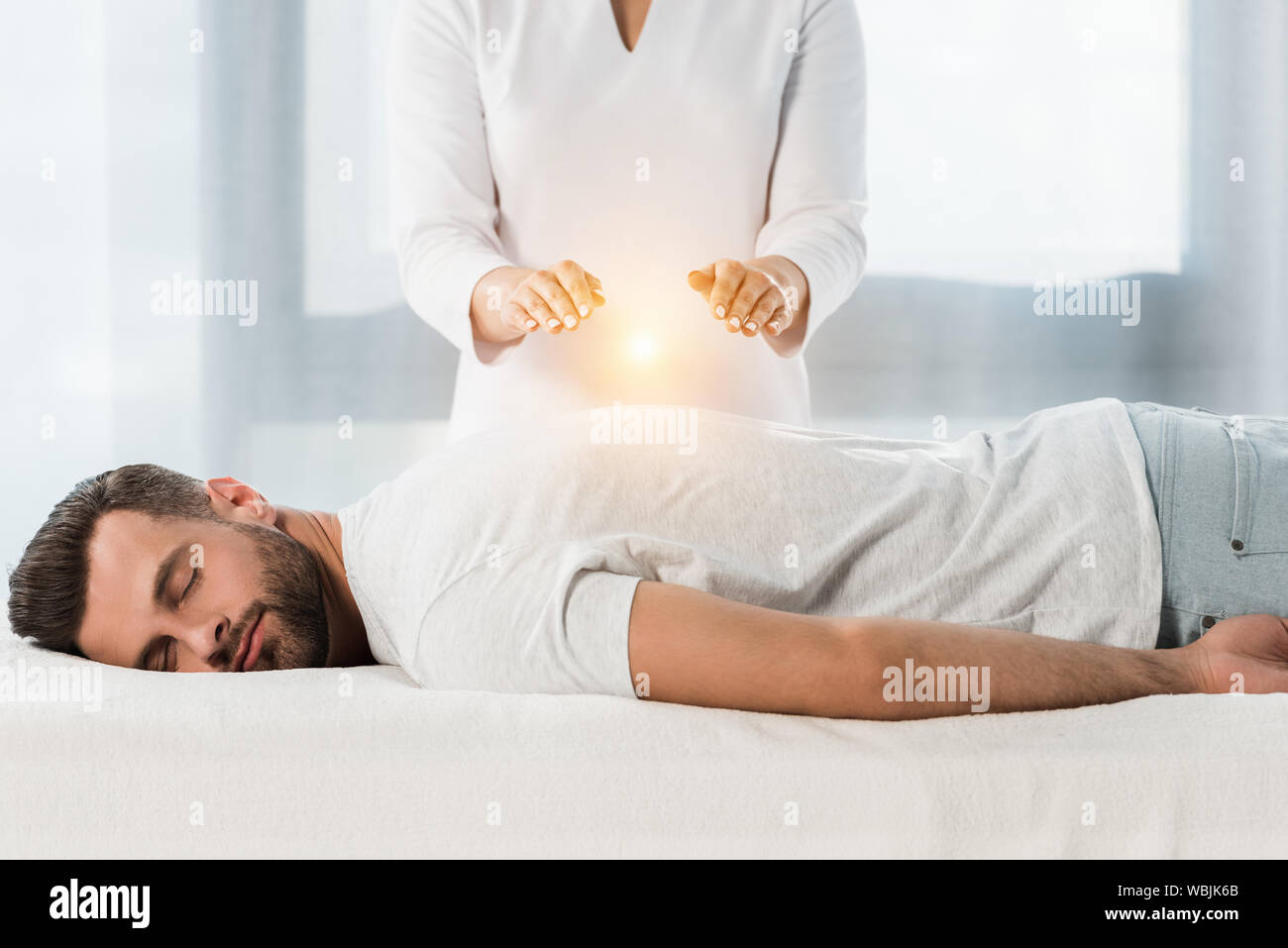 cropped view of woman healing man while putting hands above body Stock Photo