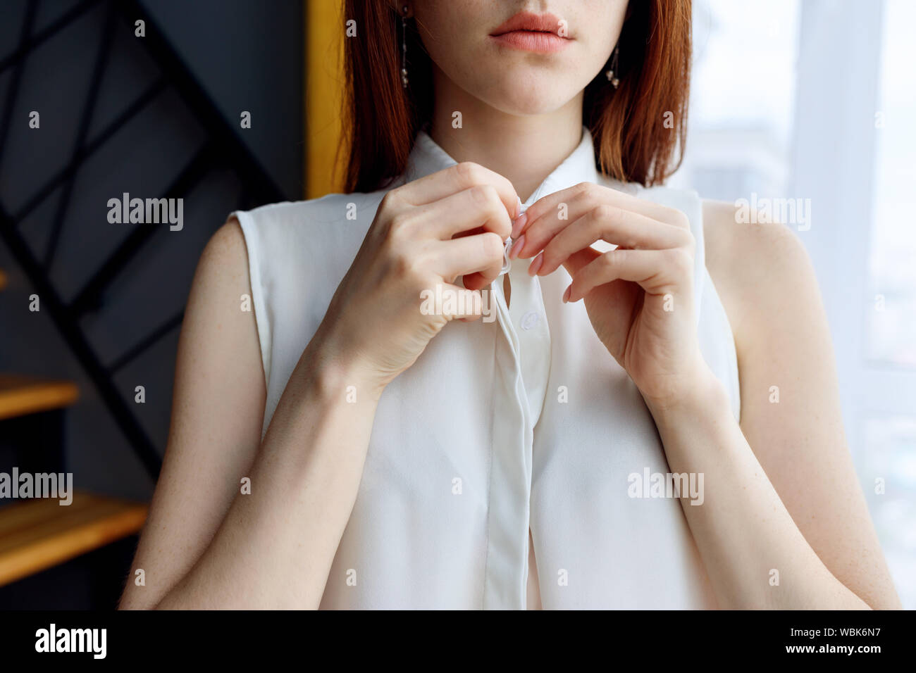 Unrecognizable redhead woman unbuttoning white blouse at home. Stock Photo
