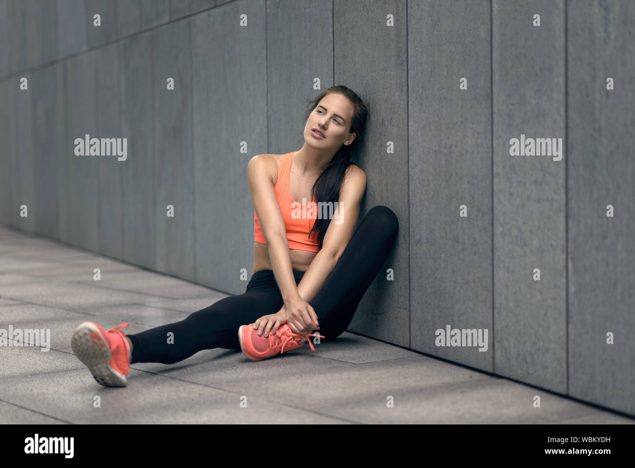 Woman In Sports Clothing Sitting Outdoors Stock Photo
