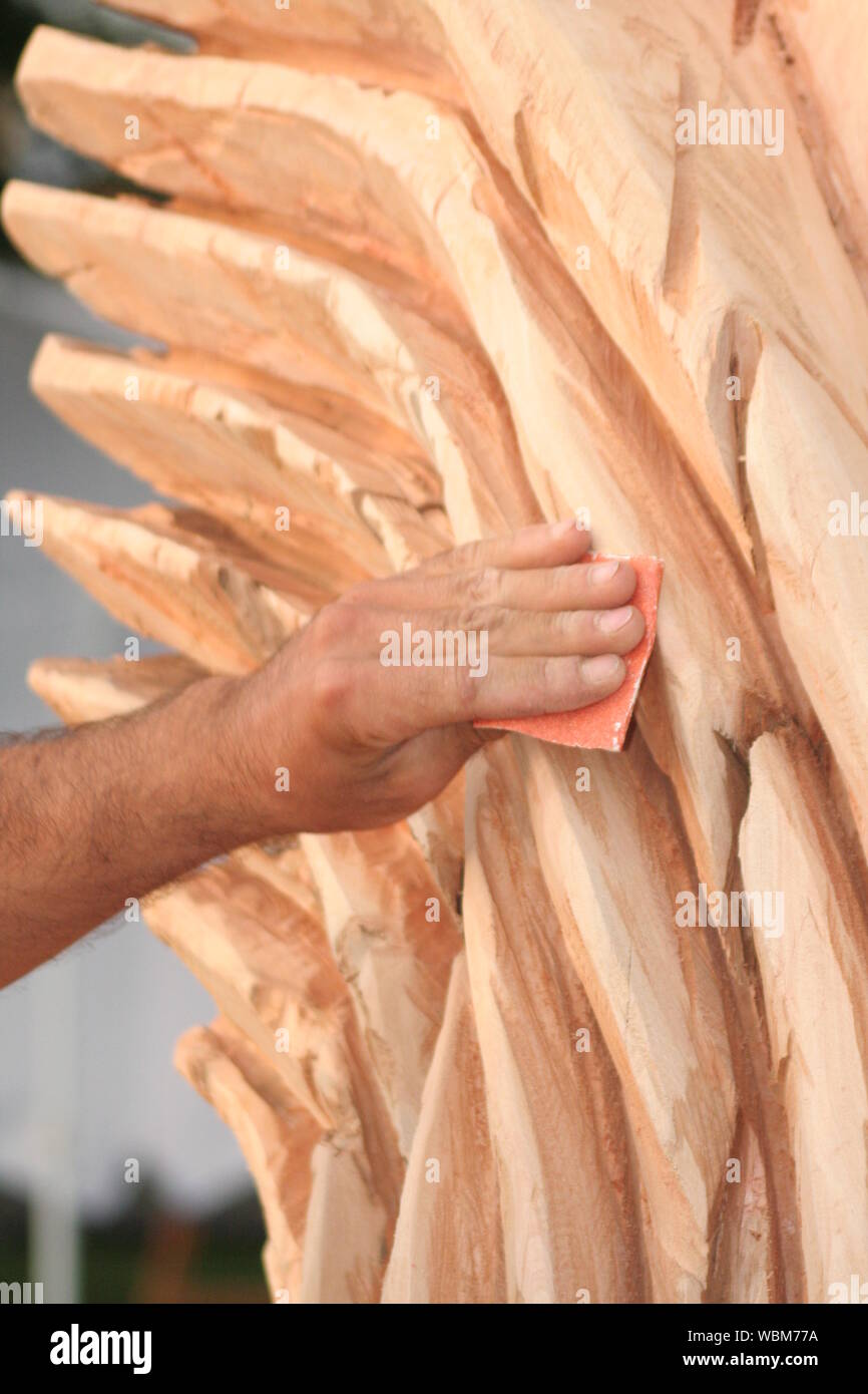 Cropped Image Of Artist Smoothing Surface Of Wood Sculpture With Sandpaper In Workshop Stock Photo